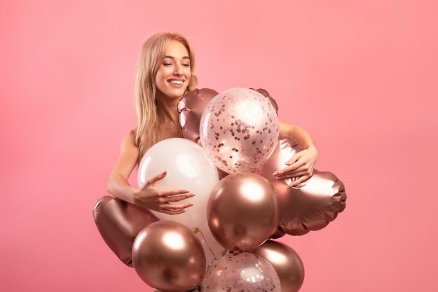 Graceful,Blonde,Birthday,Lady,Posing,With,Colorful,Balloons,Over,Pink